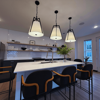 A kitchen with a white counter and black chairs.